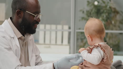 Kaukasisches-Baby-Bei-Gesundheitsuntersuchung-Mit-Afroamerikanischem-Kinderarzt